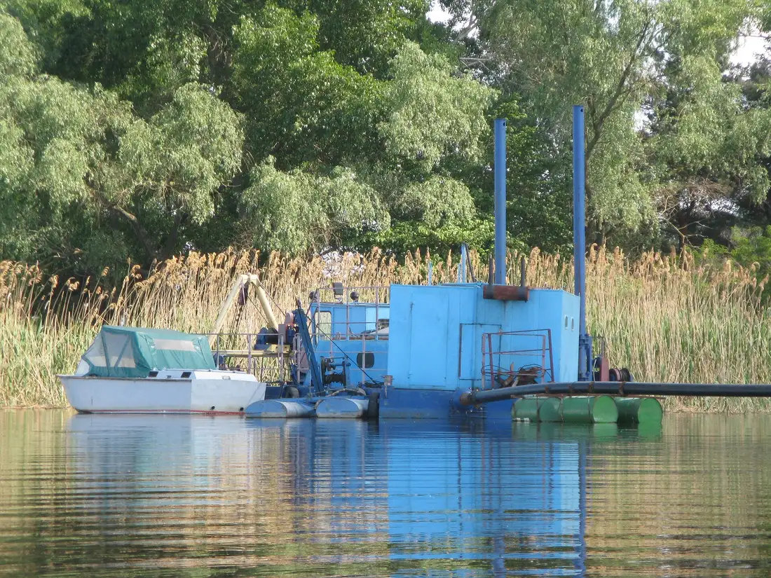 Small dredge barge working a quiet lake shoreline
