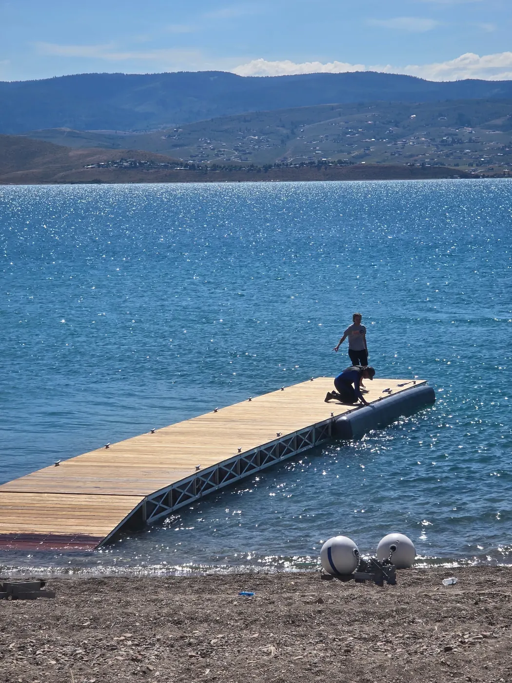 Crew connecting a pontoon float to a wood decked steel truss dock at the shoreline
