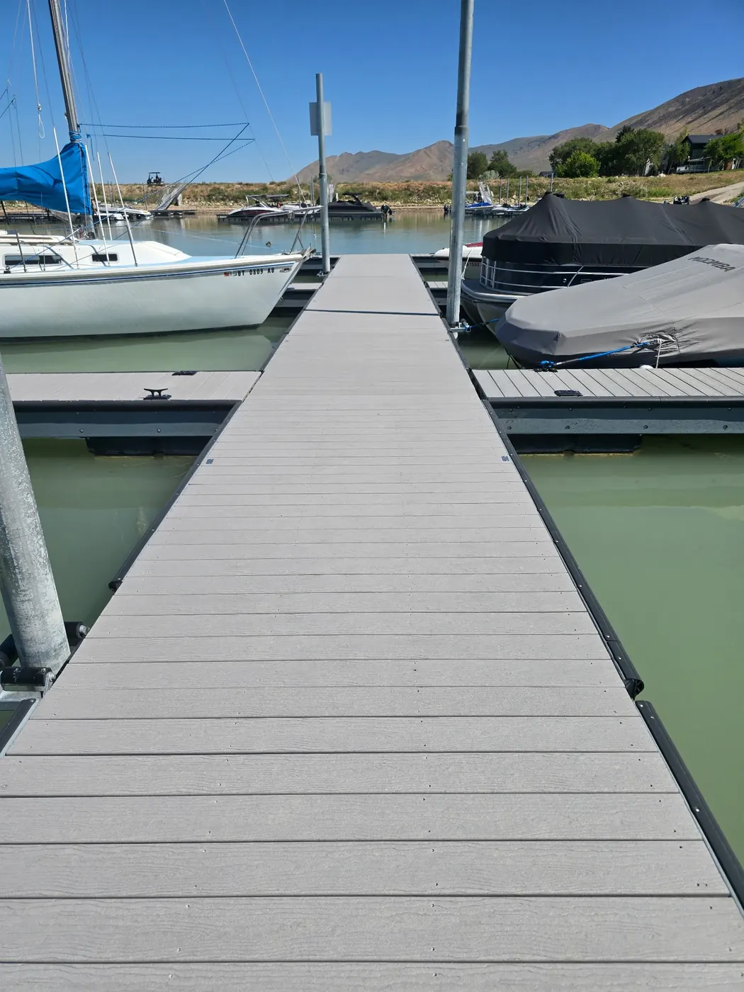 Composite decked main walk between slips holding a sailboat and covered boats