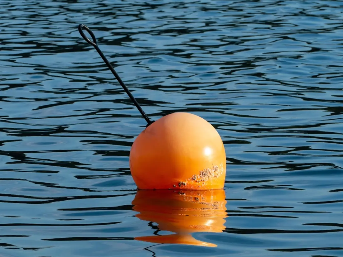 Orange mooring buoy floating on open water