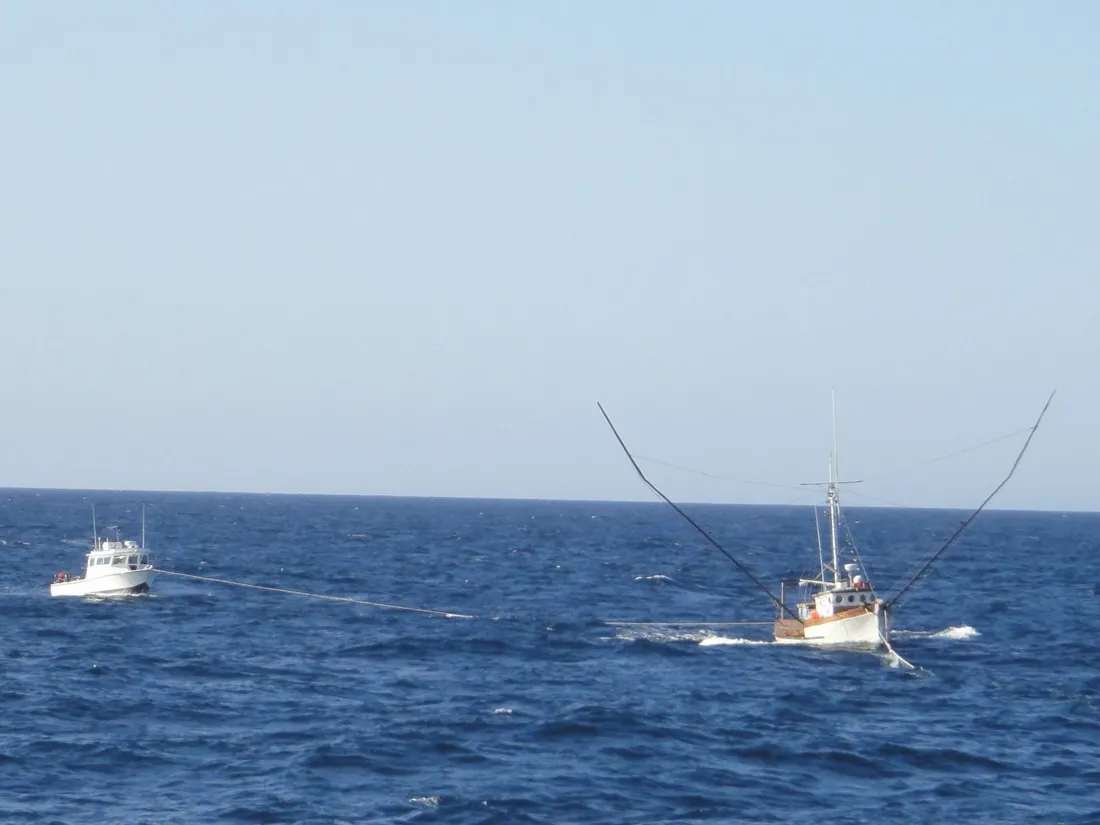 One boat towing another across open water on a line